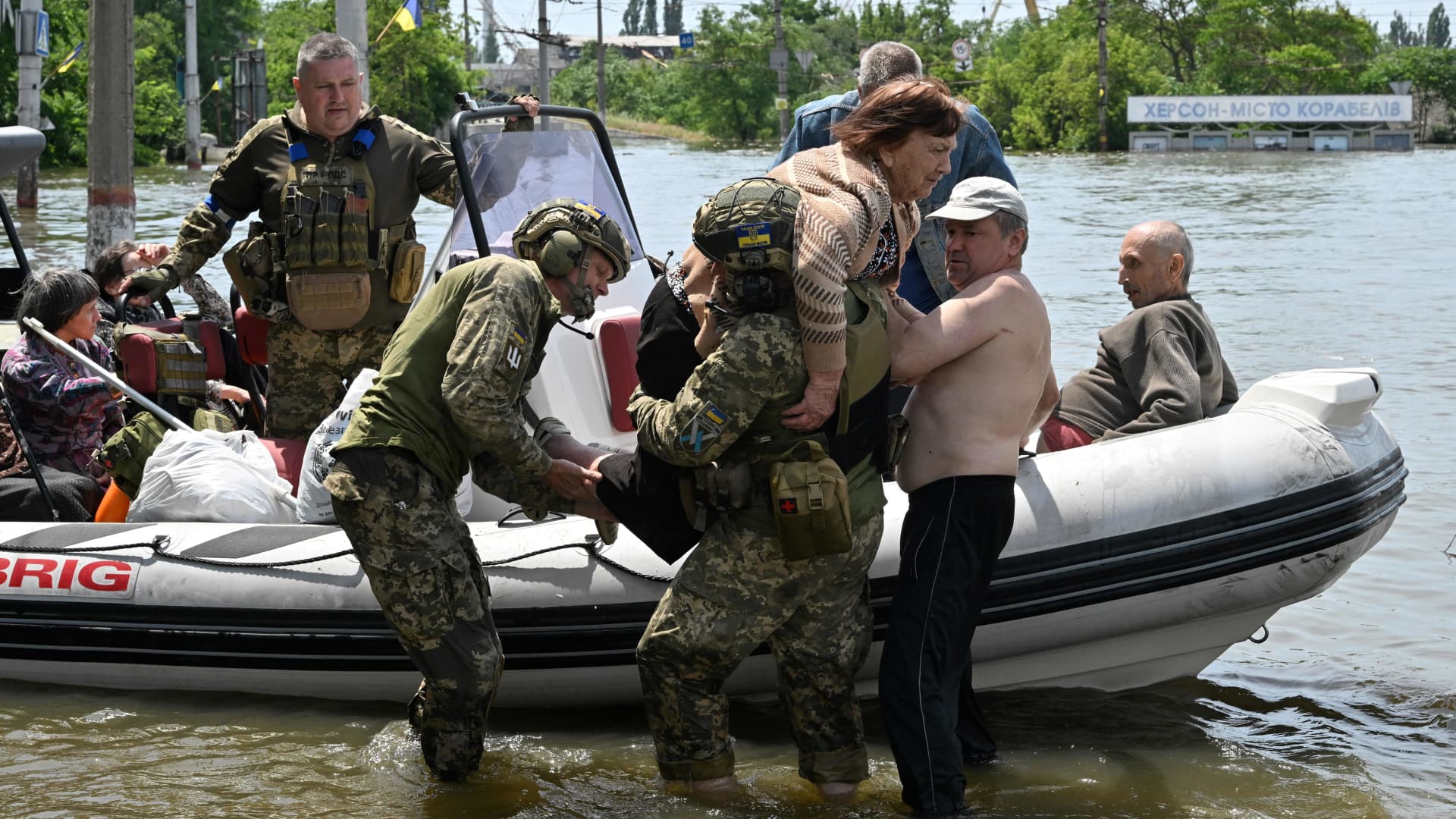 Ukrainian servicemen help to unload an elderly woman from a boat during an evacuation from a flooded area in Kherson on June 8, 2023, following damages sustained at Kakhovka hydroelectric power plant dam. 