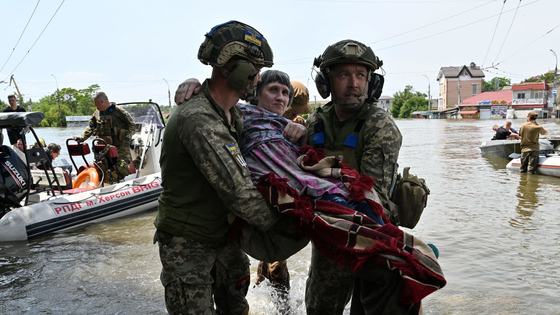 Ukrainian servicemen help to unload a disabled local resident from a boat during an evacuation from a flooded area in Kherson on June 8, 2023, following damages sustained at Kakhovka hydroelectric power plant dam. 