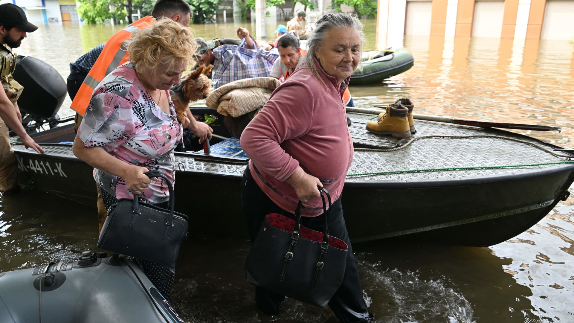 Local residents carry their belongings and pets during an evacuation from a flooded area in Kherson on June 8, 2023, following damages sustained at Kakhovka hydroelectric power plant dam. 