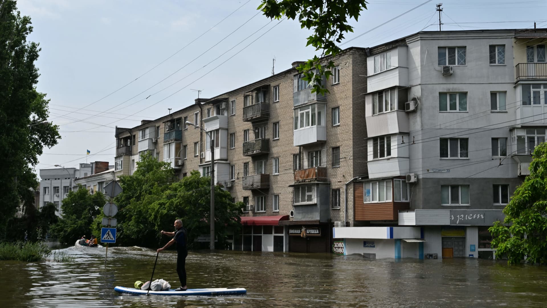 A local resident sails on a SUP board during an evacuation from a flooded area in Kherson on June 8, 2023, following damages sustained at Kakhovka hydroelectric power plant dam. 