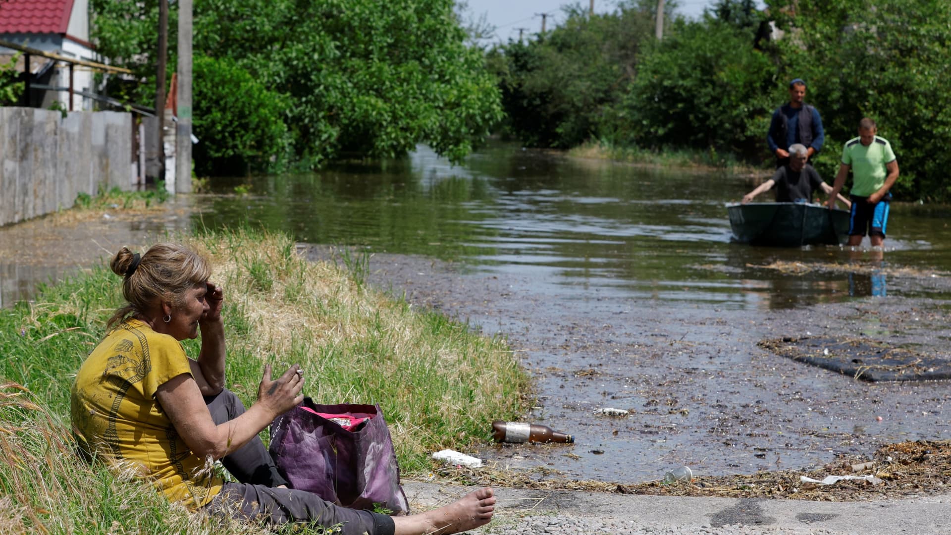 Local resident Valentina, who spent two days on the roof of a flooded house, sits on the ground after being evacuated to a non-flooded area following the collapse of the Nova Kakhovka dam in the course of Russia-Ukraine conflict, in the town of Hola Prystan in the Kherson region, Russian-controlled Ukraine, June 8, 2023. 