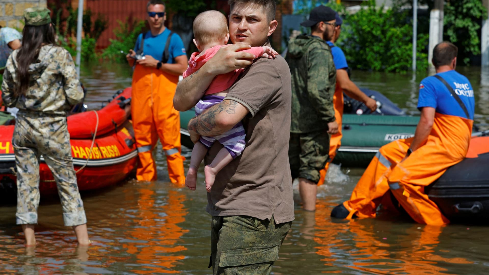 A man carries a child as members of Russia's emergencies ministry evacuate residents of a flooded area following the collapse of the Nova Kakhovka dam in the course of Russia-Ukraine conflict, in the town of Hola Prystan in the Kherson region, Russian-controlled Ukraine, June 8, 2023. 