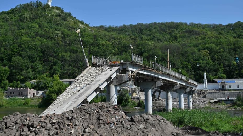 Workers clean debris of the destroyed bridge next to the Svyatogirsk Orthodox Christian Monastery in the town of Svyatogirsk, Donetsk region on June 22, 2023, amid the Russian invasion of Ukraine. (Photo by Genya SAVILOV / AFP) (Photo by GENYA SAVILOV/AFP via Getty Images)