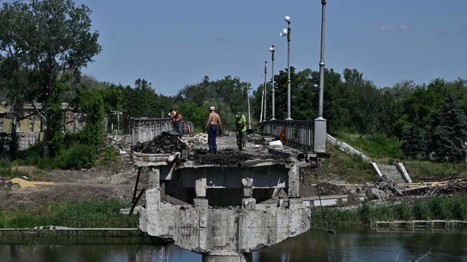 TOPSHOT - Workers clean debris of the destroyed bridge next to the Svyatogirsk Orthodox Christian Monastery in the town of Svyatogirsk, Donetsk region on June 22, 2023, amid the Russian invasion of Ukraine. (Photo by Genya SAVILOV / AFP) (Photo by GENYA SAVILOV/AFP via Getty Images)