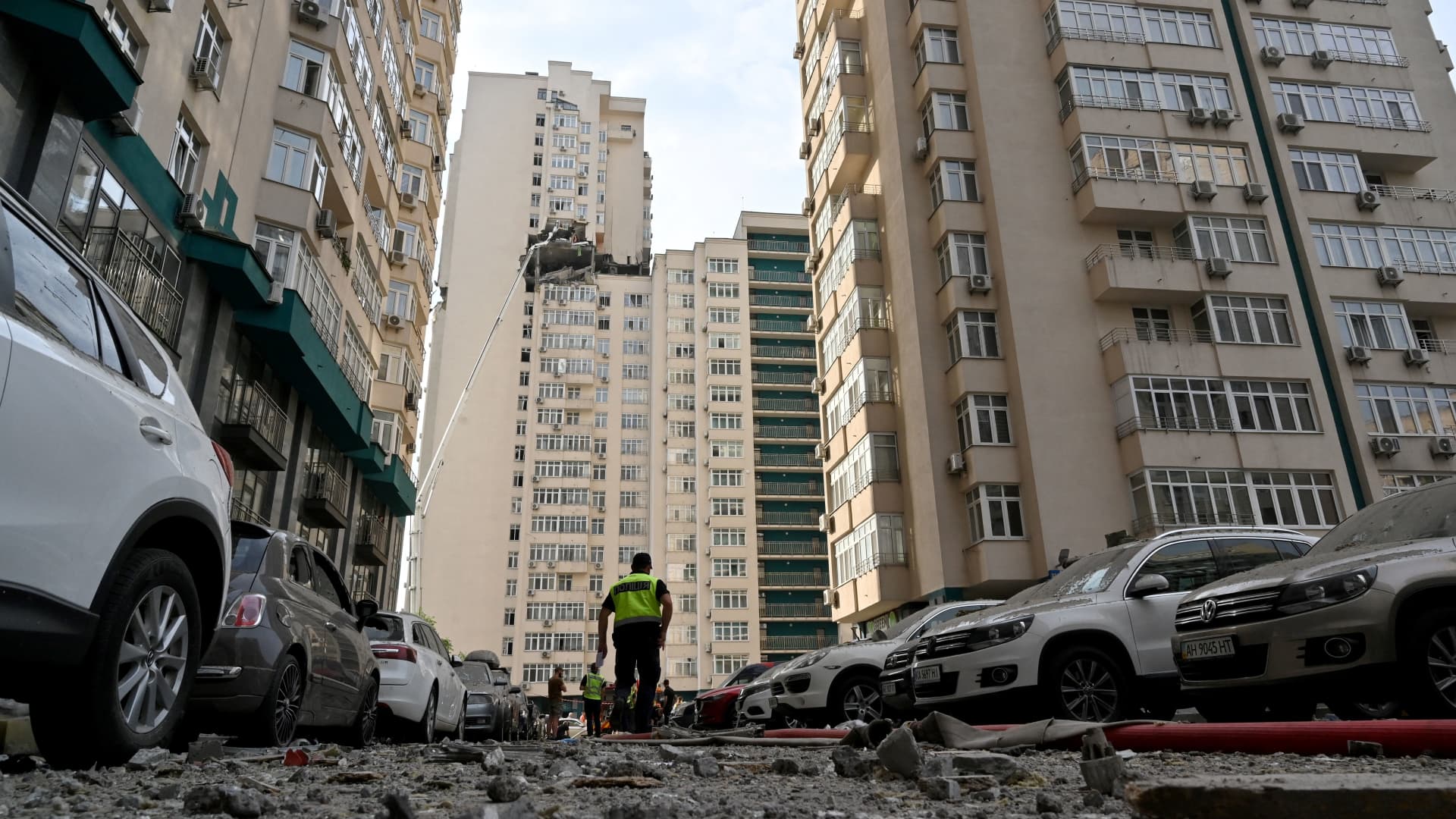 A Ukrainian police officer walks past a 24-storey building partially destroyed following a Russian missiles strike in Kyiv early on June 24, 2023.
