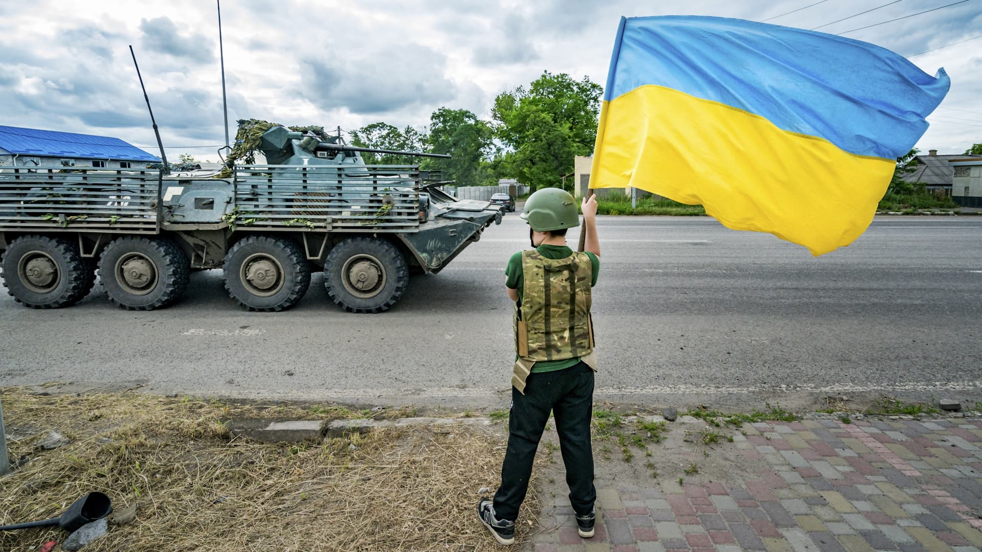 A boy waves a Ukrainian flag as an armored vehicle from the Ukrainian army goes to the Bakhmut frontlines, In Sloviansk, on june 27, 2023. 