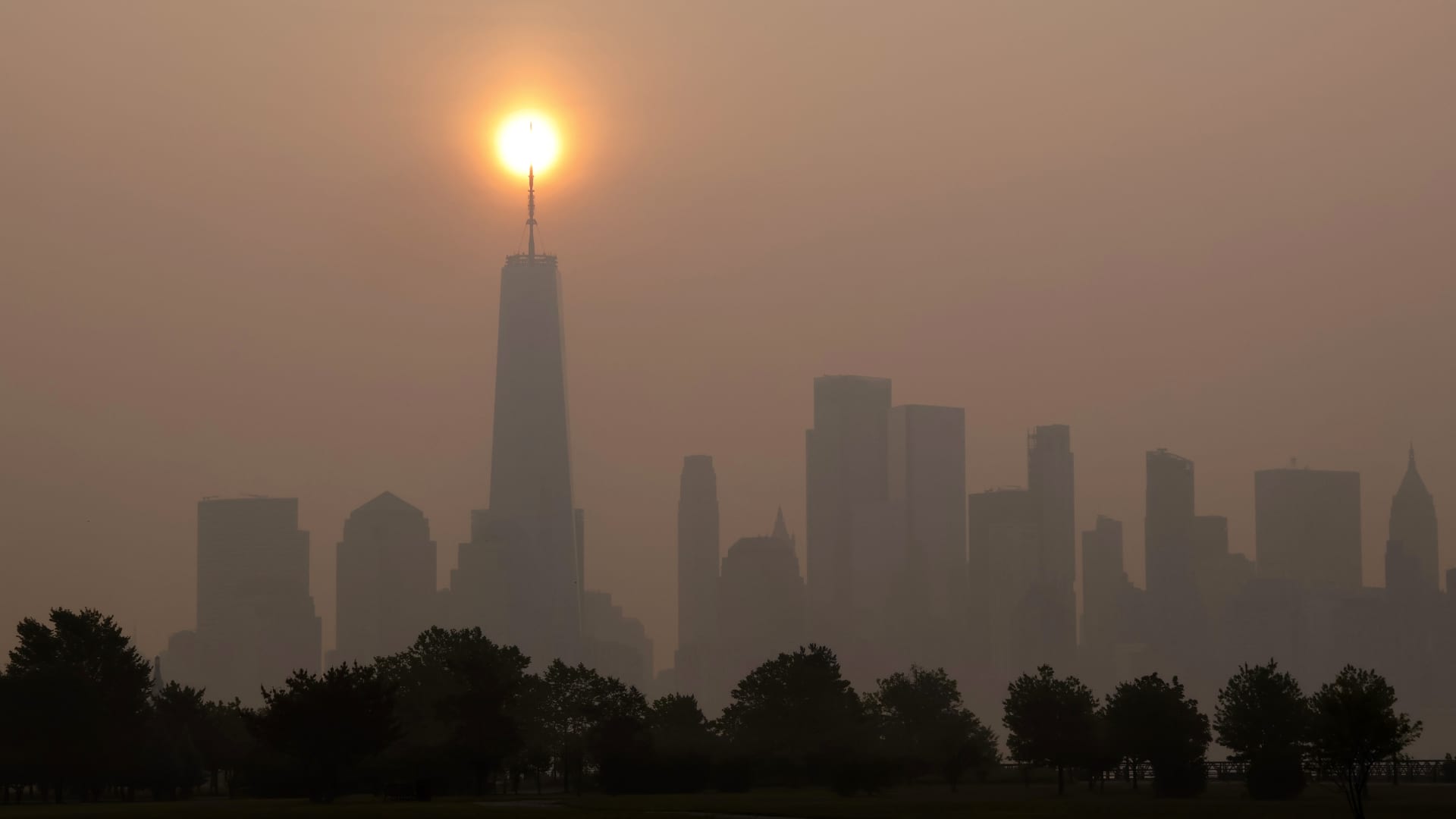 Smoke shrouds the skyline of lower Manhattan and One World Trade Center as the sun rises in New York City on June 30, 2023, as seen from Jersey City, New Jersey.