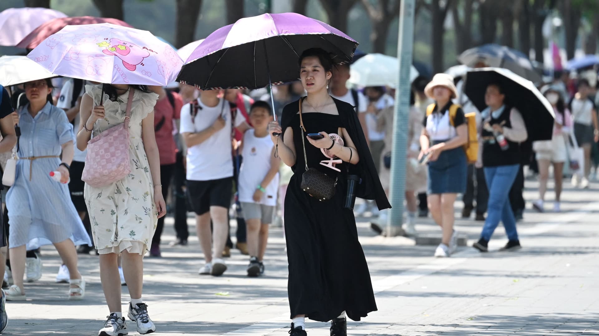 People shelter from the sun under umbrellas after visiting the Forbidden City during a heatwave in Beijing on June 24, 2023. Beijing recorded its third consecutive day of 40 degree Celsius weather, the first time since records began.