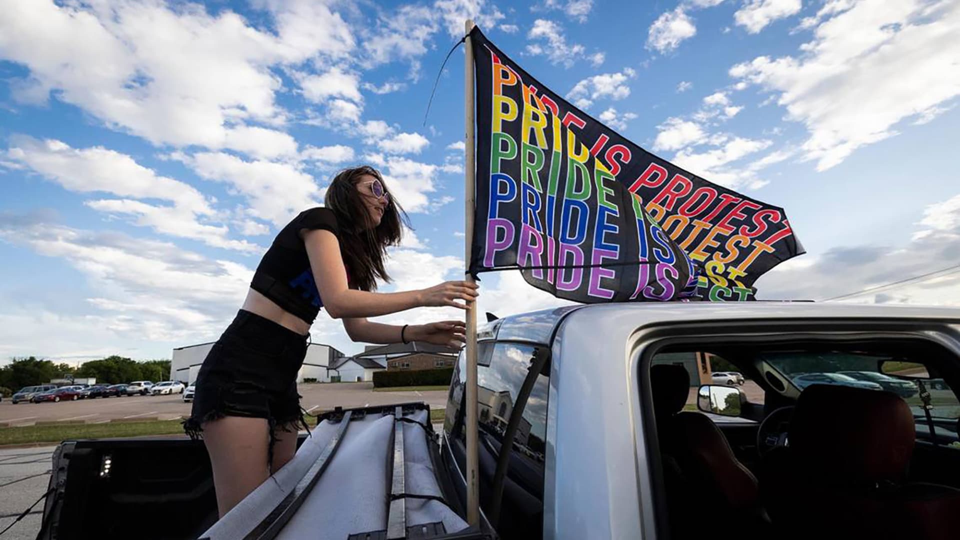 Hillary Ward puts up a Pride flag while protesting near Stedfast Baptist Church where a pastor preaches against homosexuality, on June 1, 2022, in Watauga, Texas.