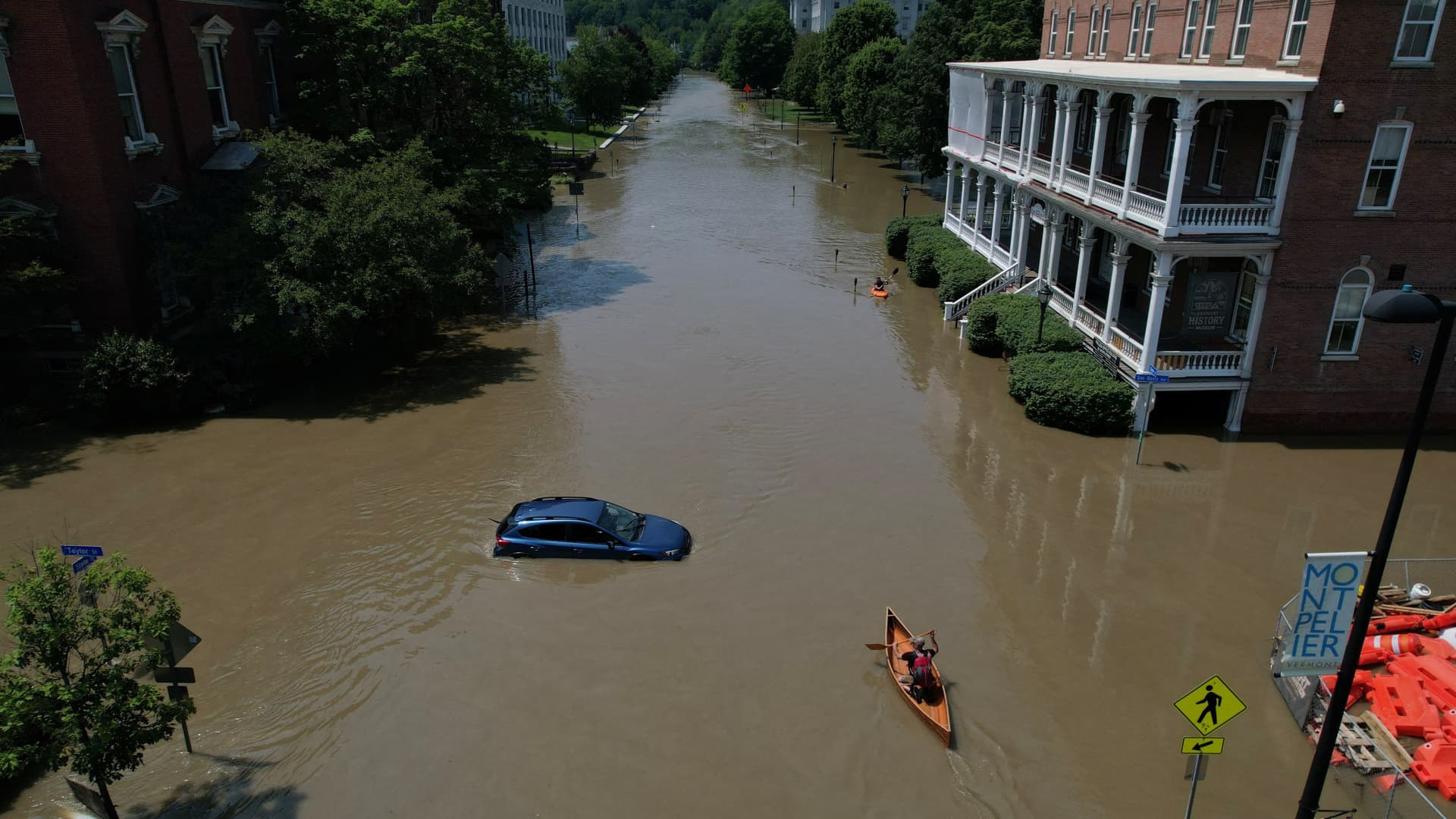 A person paddles a canoe down a street flooded by recent rain storms in Montpelier, Vermont, July 11, 2023.