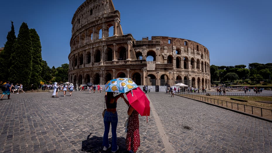 ROME, ITALY - JULY 18: Tourists with umbrellas to protect themselves from the sun at Colosseo area (Colosseum), during the ongoing heat wave with temperatures reaching 45 degrees on July 18, 2023 in Rome, Italy. The government has issued red alerts for 16 cities due to the current heatwave, which the Italian Meteorological Society named Cerberus, the mythical creature who guarded the gates of the underworld. Many places in Italy have seen successive days over 40C. (Photo by Stefano Montesi - Corbis/Getty Im
