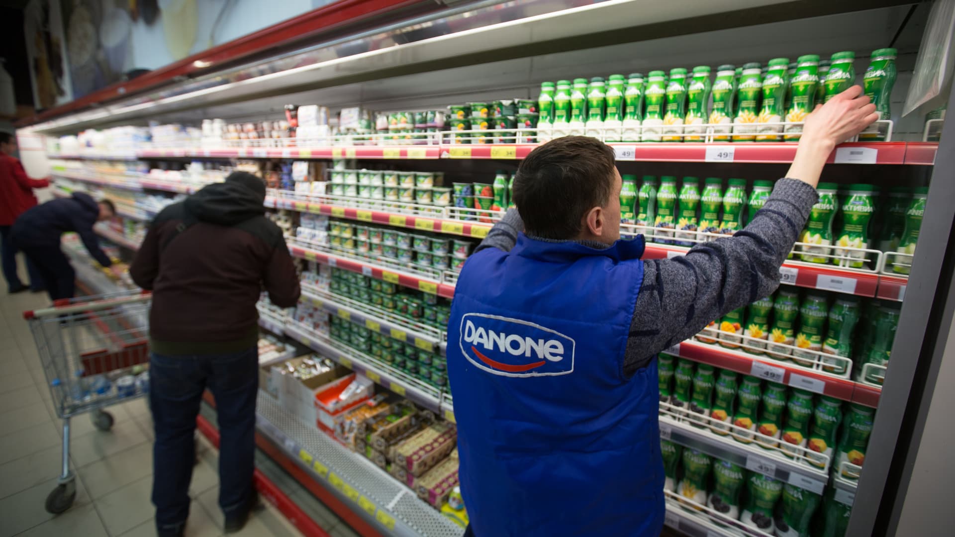 An employee wearing a Danone SA branded gilet stacks bottles of yoghurt inside a Magnit PJSC hypermarket store at the Hanoi-Moscow trade centre in Moscow, Russia, on Wednesday, Feb. 28, 2018.