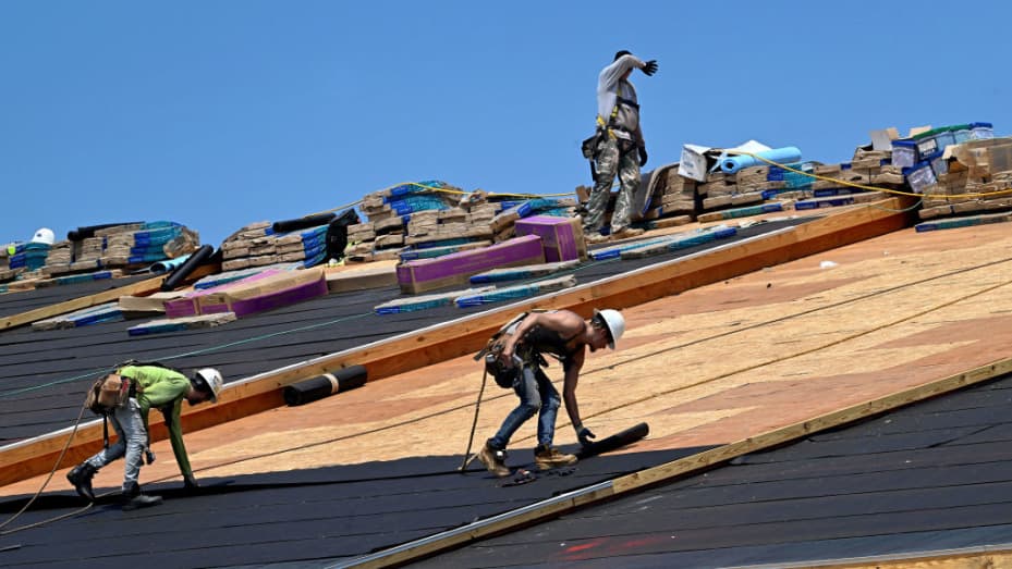 As one construction worker wipes his brow, two other roofers work under a 90 degree temperature at a housing complex under construction in Clarksburg, Maryland on July 26, 2023.