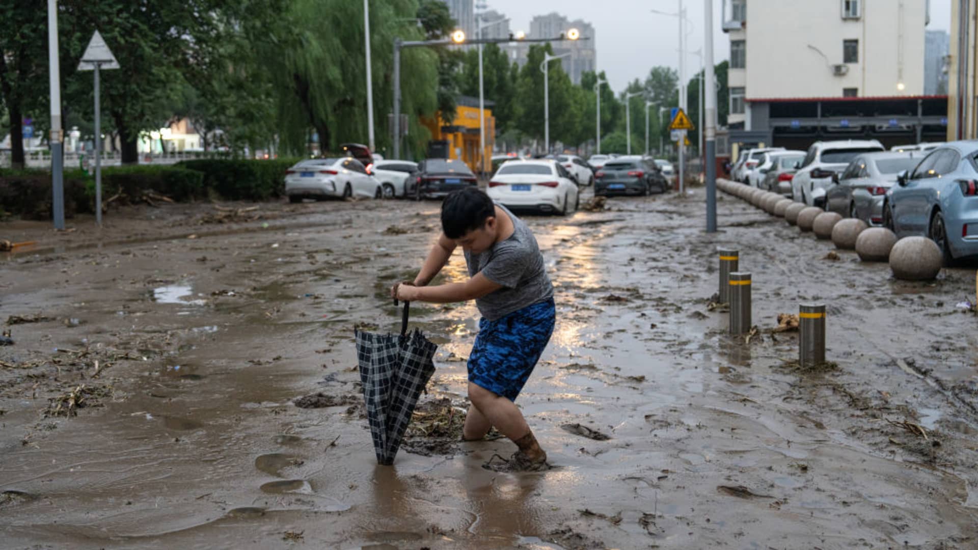A child walking through muddy water in Mengtougou district after flood water recedes on July 31, 2023 in Beijing, China.