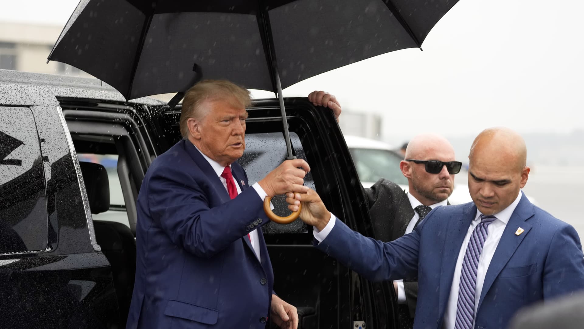 Valet Walt Nauta hands former President Donald Trump an umbrella before he speaks at Ronald Reagan Washington National Airport, Thursday, Aug. 3, 2023, in Arlington, Va., after facing a judge on federal conspiracy charges that allege he conspired to subvert the 2020 election