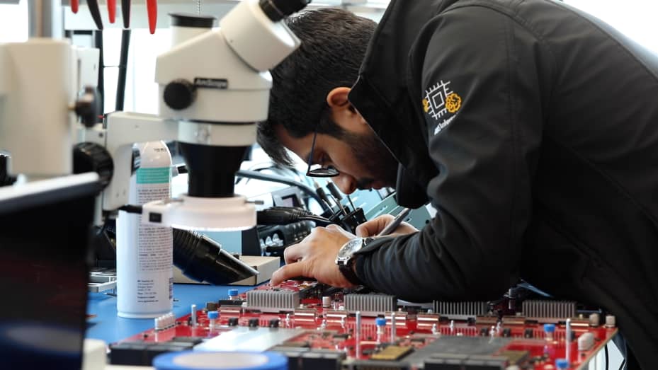 An Amazon employee works on custom AI chips, in a jacket branded with AWS' chip Inferentia, at the AWS chip lab in Austin, Texas, on July 25, 2023.