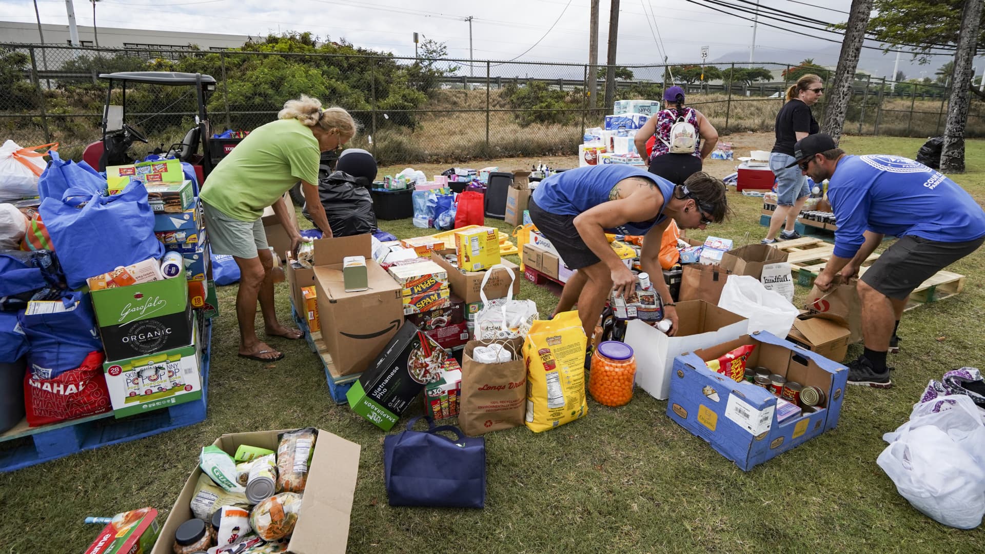 Volunteers stack canned goods at War Memorial Stadium in Kahului, Hawaii on August 10, 2023. 