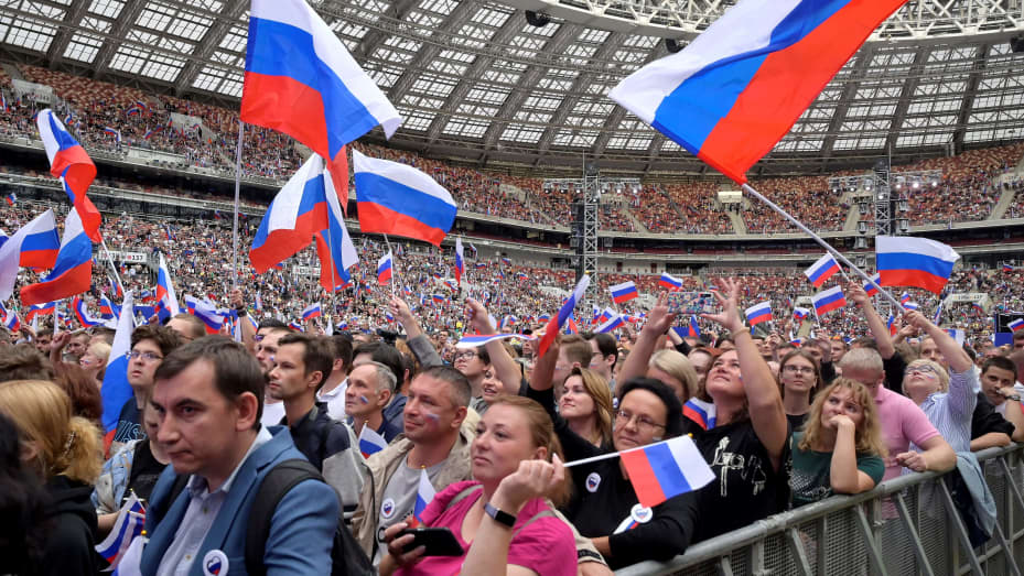 Personas sostienen banderas rusas mientras asisten a un concierto que conmemora el Día de la Bandera Nacional de Rusia en el estadio Luzhniki de Moscú, el 22 de agosto de 2023. (Foto de Natalia KOLESNIKOVA / AFP) (Foto de NATALIA KOLESNIKOVA/AFP vía Getty Images)