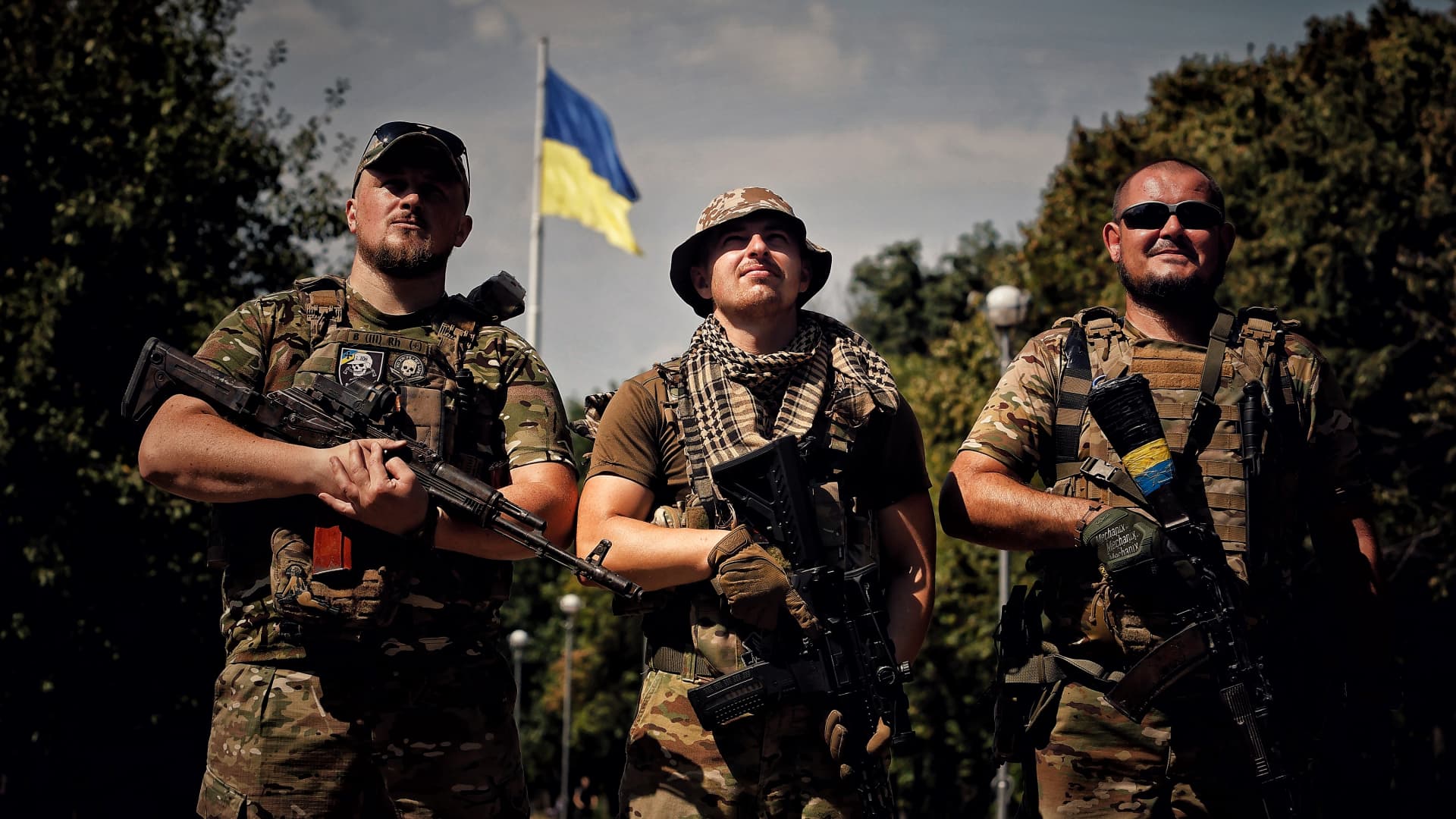 Ukrainian soldiers pose for a photo in front of the Ukrainian flag on August 22, 2023 in Kramatorsk, Ukraine. 