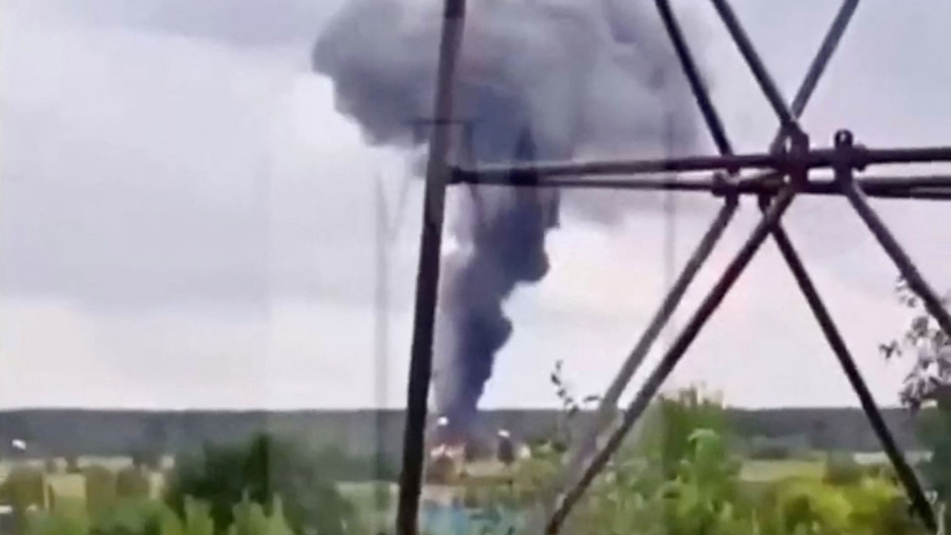 A view shows smoke rising above a plane on fire following an alleged air accident at a location given as Tver region, Russia, in this still image from video published August 23, 2023. Watermark from source.