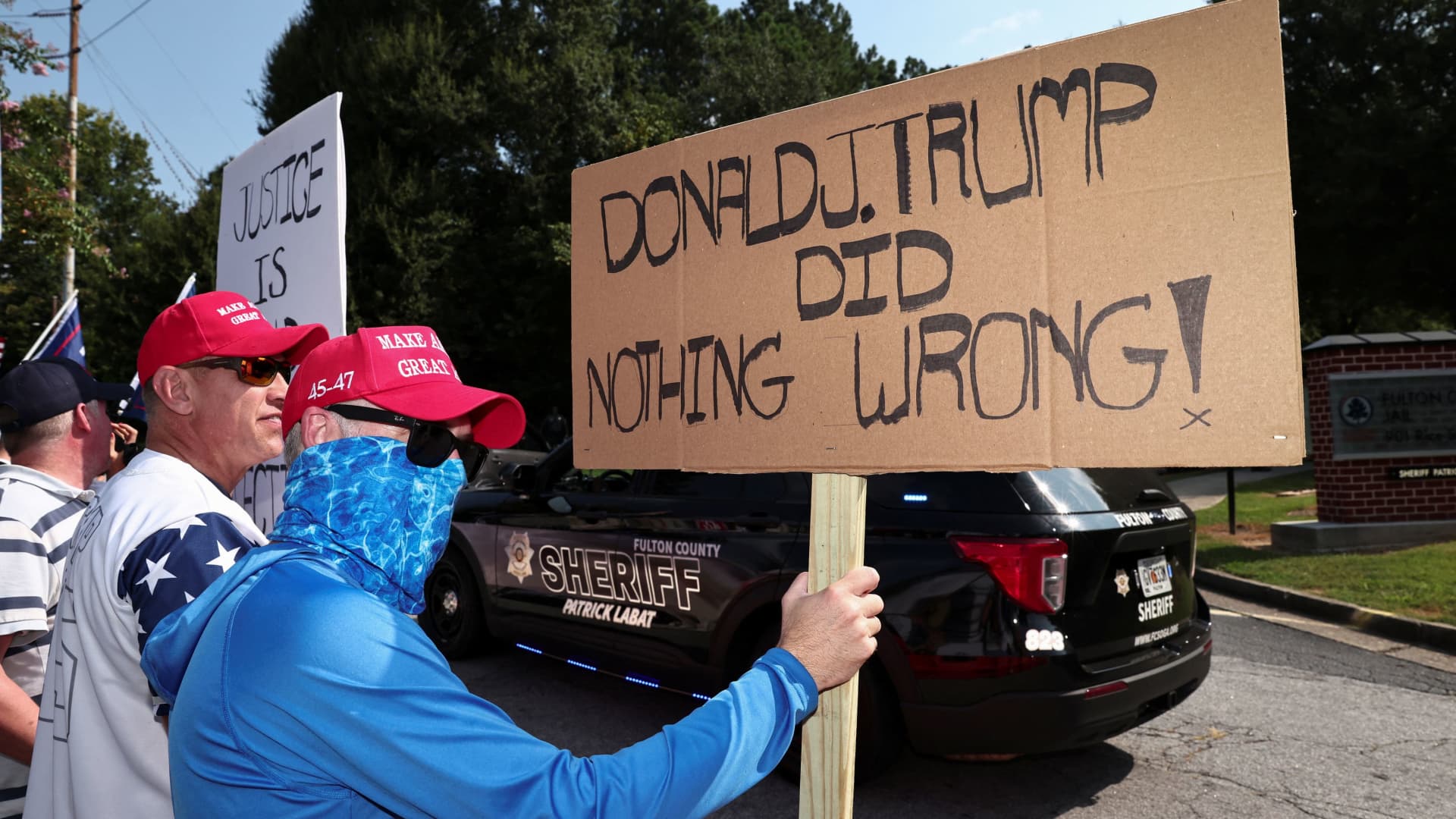 A supporter of former U.S. President Donald Trump holds a banner at the entrance of the Fulton County Jail, as Donald Trump is expected to turn himself in to be processed after his Georgia indictment, in Atlanta, Georgia, August 24, 2023.