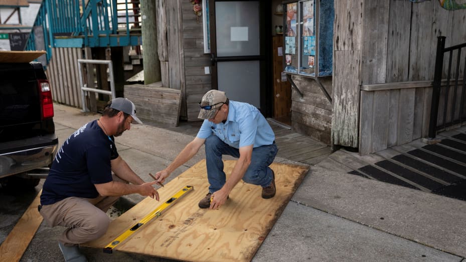 Los hombres cortaron madera contrachapada frente a una tienda antes de la llegada del huracán Idalia en Cedar Key, Florida, EE.UU., 29 de agosto de 2023. REUTERS/Marco Bello