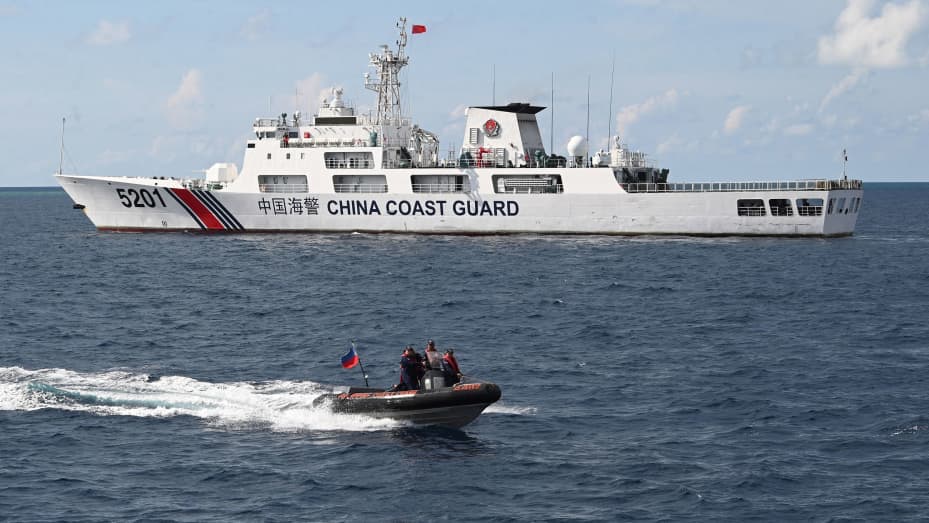 This photo taken on April 23, 2023 shows Philippine coast guard personnel aboard their rigid inflatable boat speeding past a Chinese coast guard ship after conducting a survey at Second Thomas Shoal in the Spratly Islands in the disputed South China Sea. - AFP was one of several media outlets invited to join two Philippine Coast Guard boats on a 1,670-kilometre (1,040-mile) patrol of the South China Sea, visiting a dozen islands and reefs. Beijing claims sovereignty over almost the entire South China Sea, i