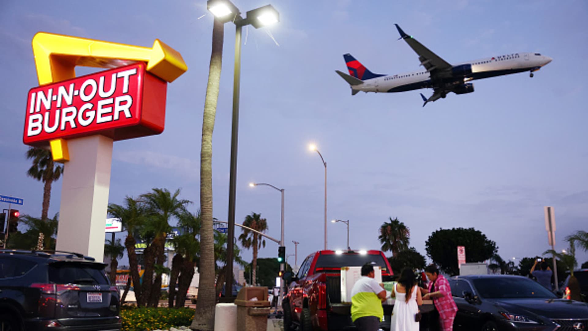 A Delta Airlines plane lands as people gather in the parking lot of In-N-Out Burger next to Los Angeles International Airport (LAX) on August 31, 2023 in Los Angeles, California.