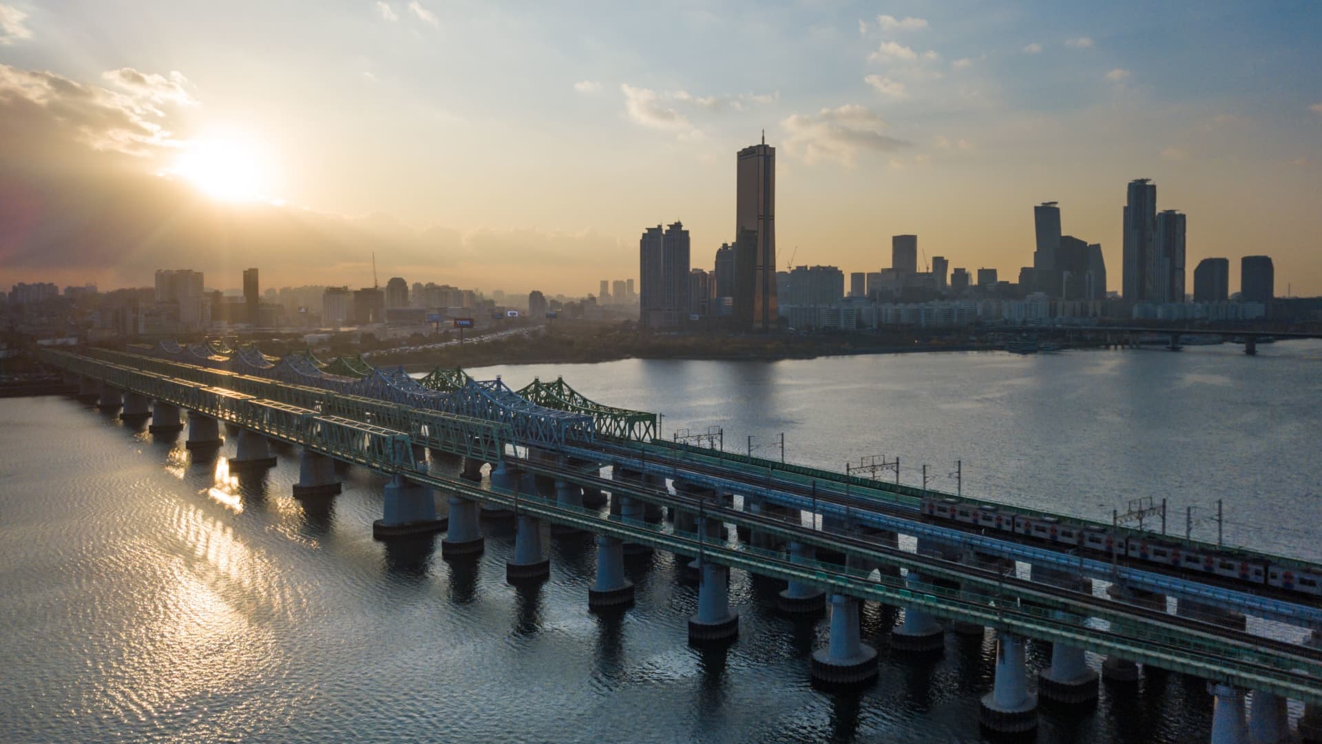 In a photo taken on November 4, 2019 a subway train crosses a rail bridge over the Han river, before the skyline of the Yeouido business district of Seoul.