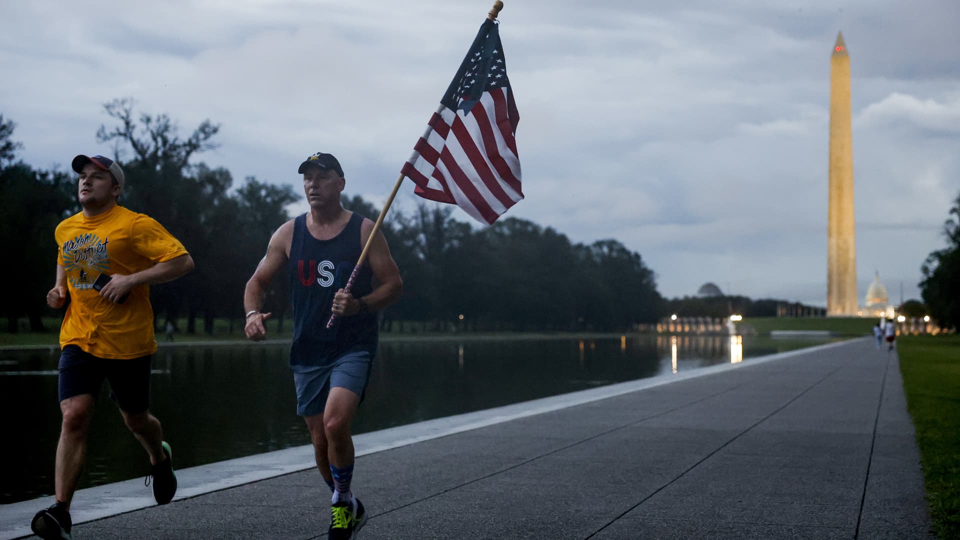 A jogger carries the American flag while running along the National Mall in Washington, D.C., on Sept. 11, 2023.