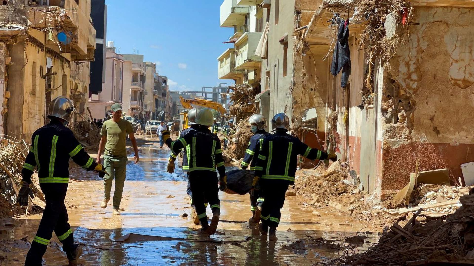 Members of the rescue teams from the Egyptian army carry a dead body as they walk in the mud between the destroyed buildings, after a powerful storm and heavy rainfall hit Libya, in Derna, Libya September 13, 2023. 