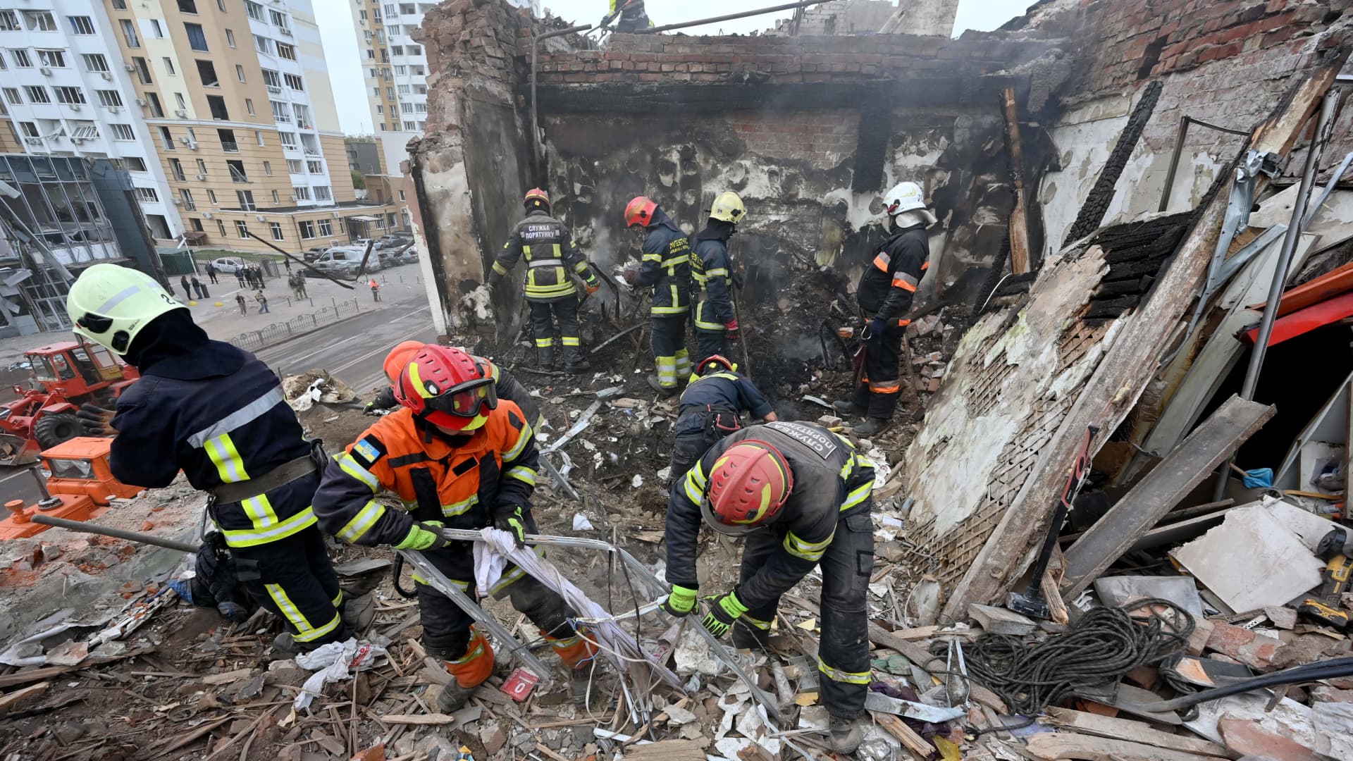 Rescuers stand atop a destroyed residential building as they clear debris following a Russian missile strike in Kharkiv on October 6, 2023, amid the Russian invasion in Ukraine.