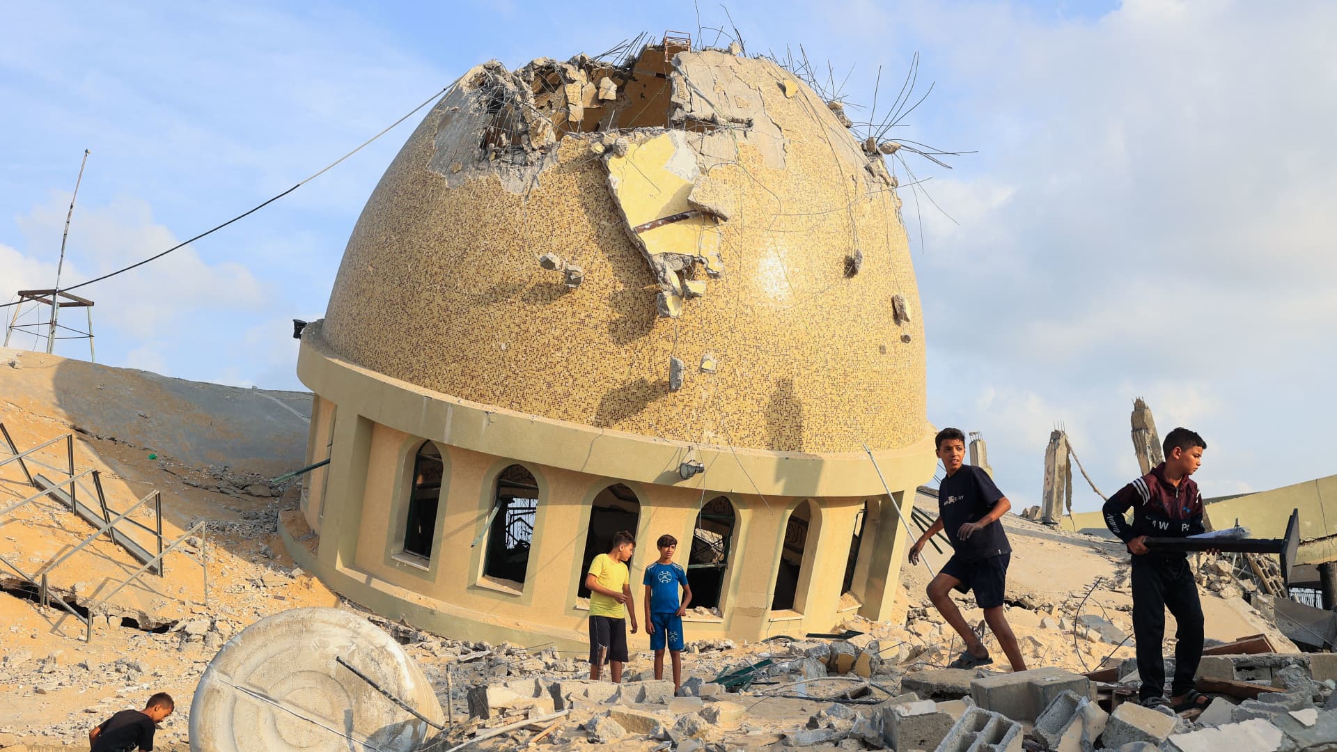 Children walk on the ruins of a mosque destroyed in Israeli airstrikes in Khan Yunis, southern Gaza Strip, on October 8, 2023.