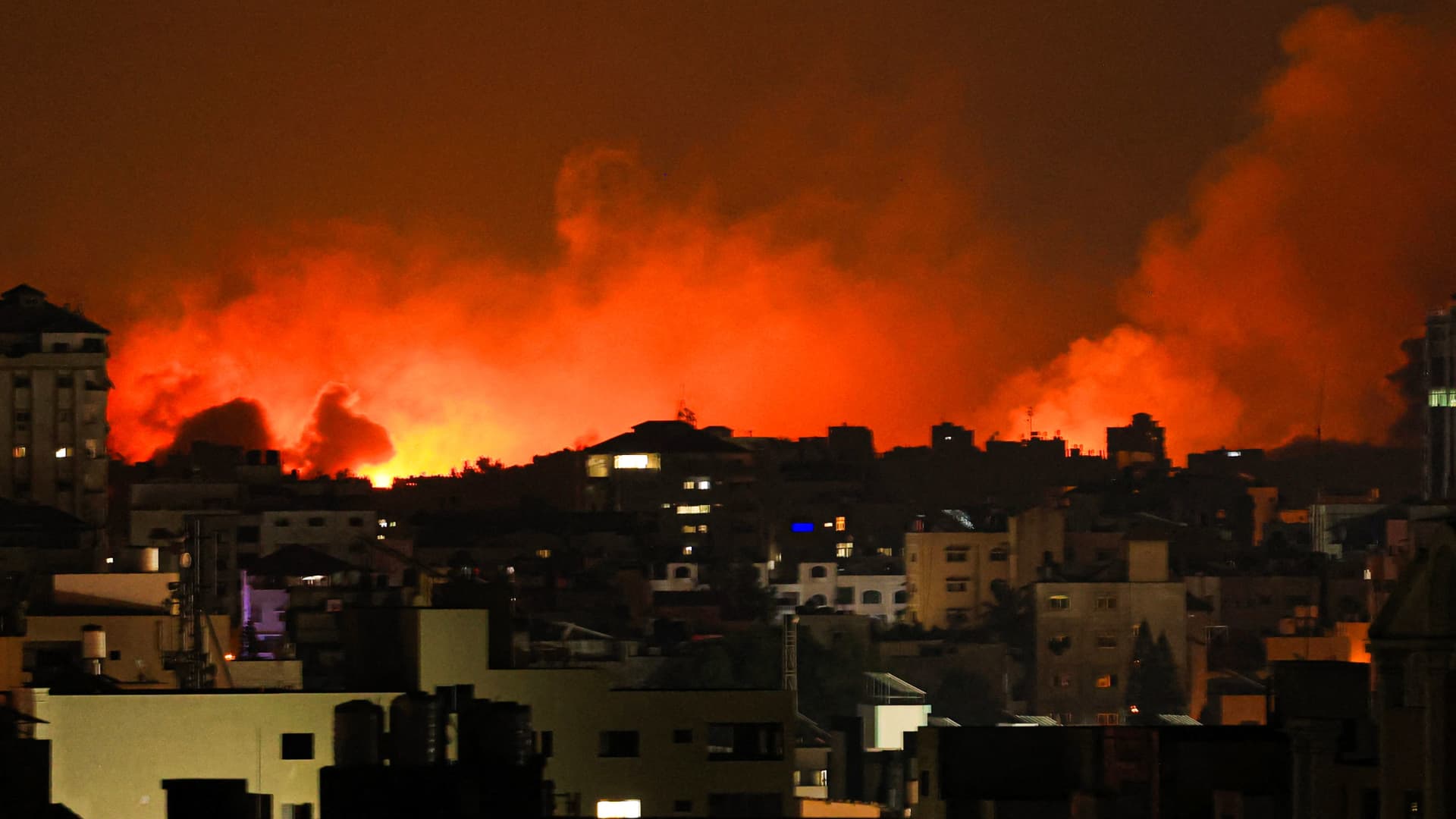 A plume of smoke rises above buildings in Gaza City during an Israeli air strike, on October 8, 2023. 