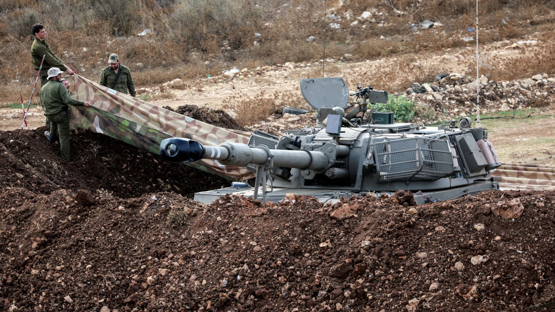 Israeli soldiers arrange the area surrounding a tank near Israel's border with Lebanon, northern Israel, October 9, 2023.