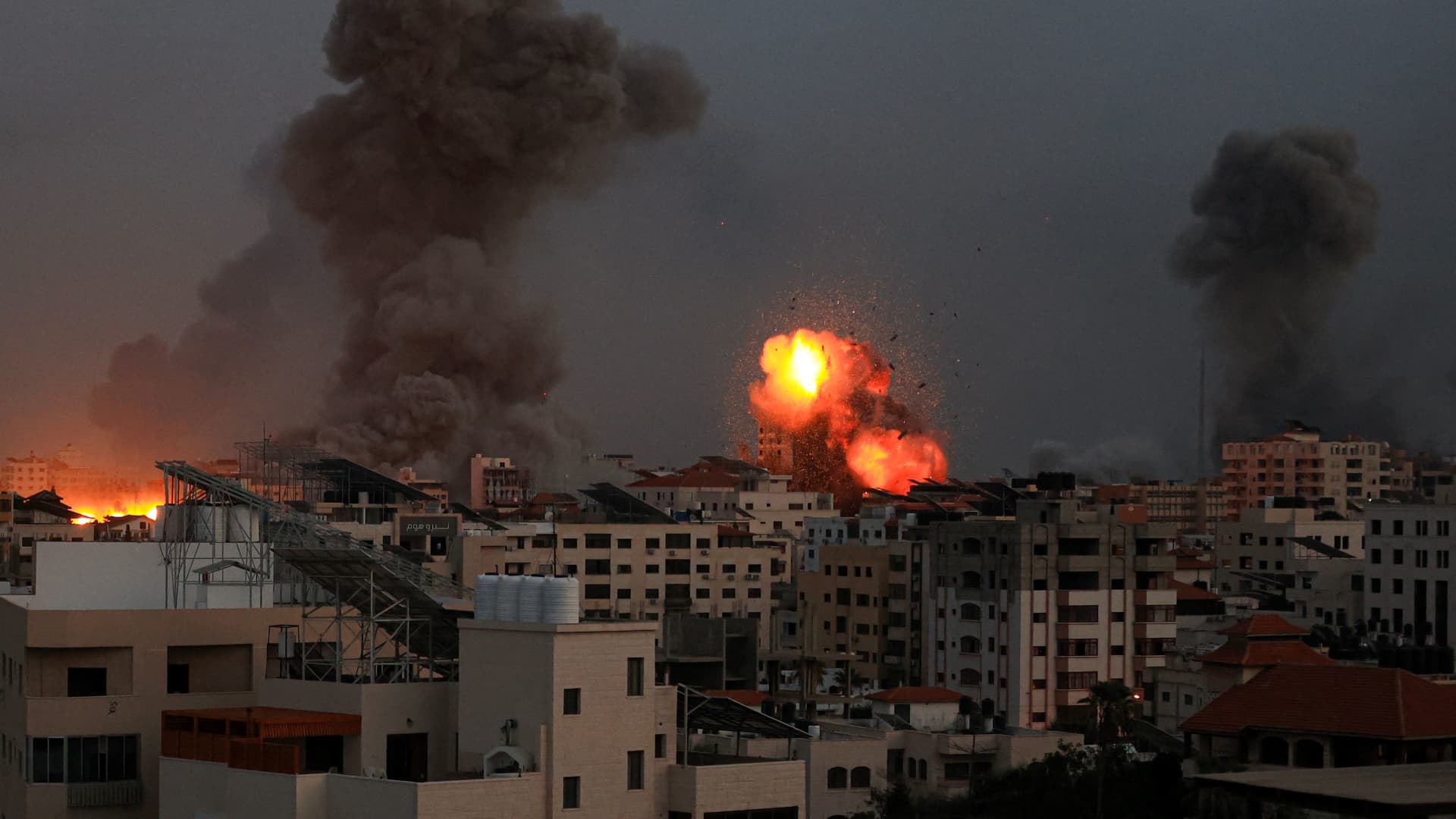 Smoke billows and debris flies in the air as the night falls on Gaza City during Israeli airstrikes on October 9, 2023. 