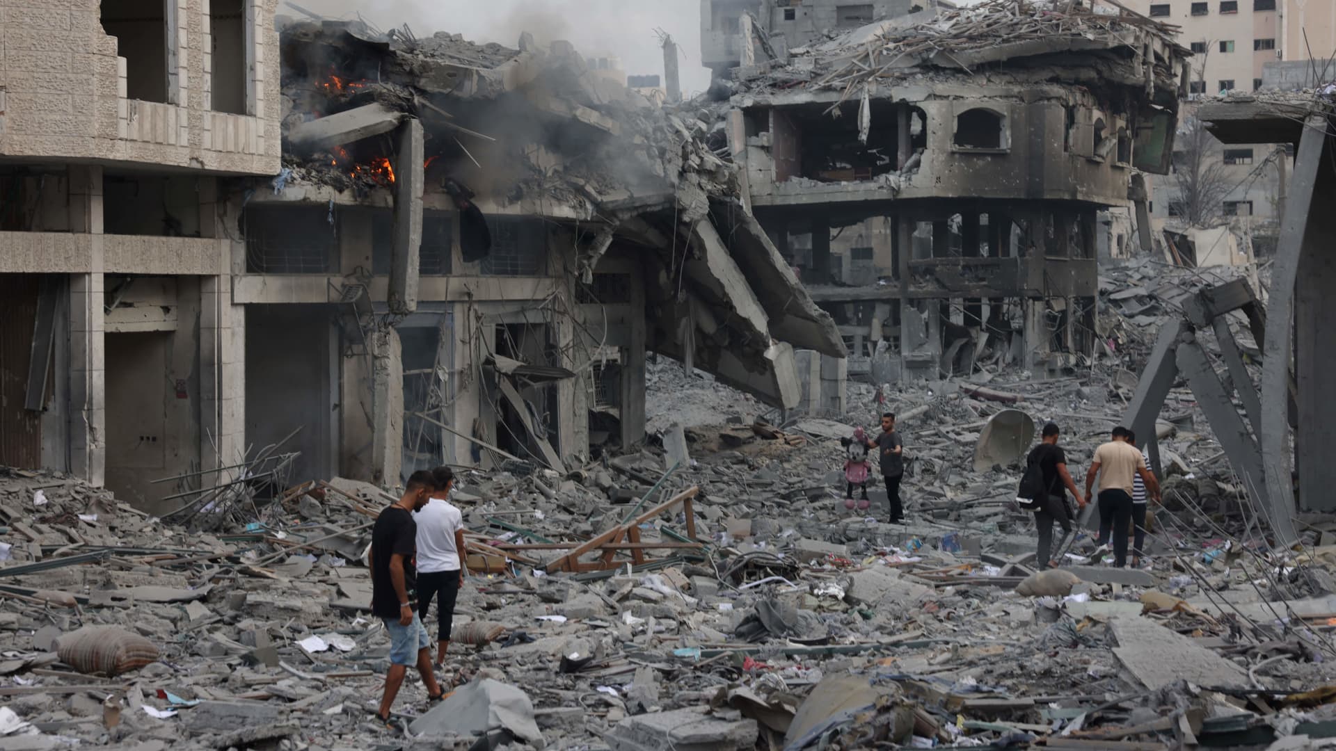 Palestinians walk through debris amid the destruction from Israeli airstrikes in Gaza City's al-Rimal neighbourhood on October 10, 2023. 