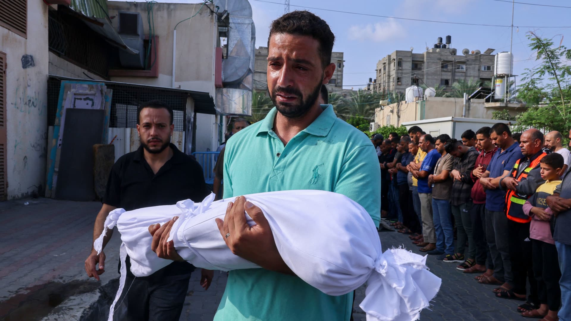 A Palestinian man carries the body of a child killed in overnight Israeli shelling during a funeral in Khan Yunis in the southern Gaza Strip, on October 10, 2023. 