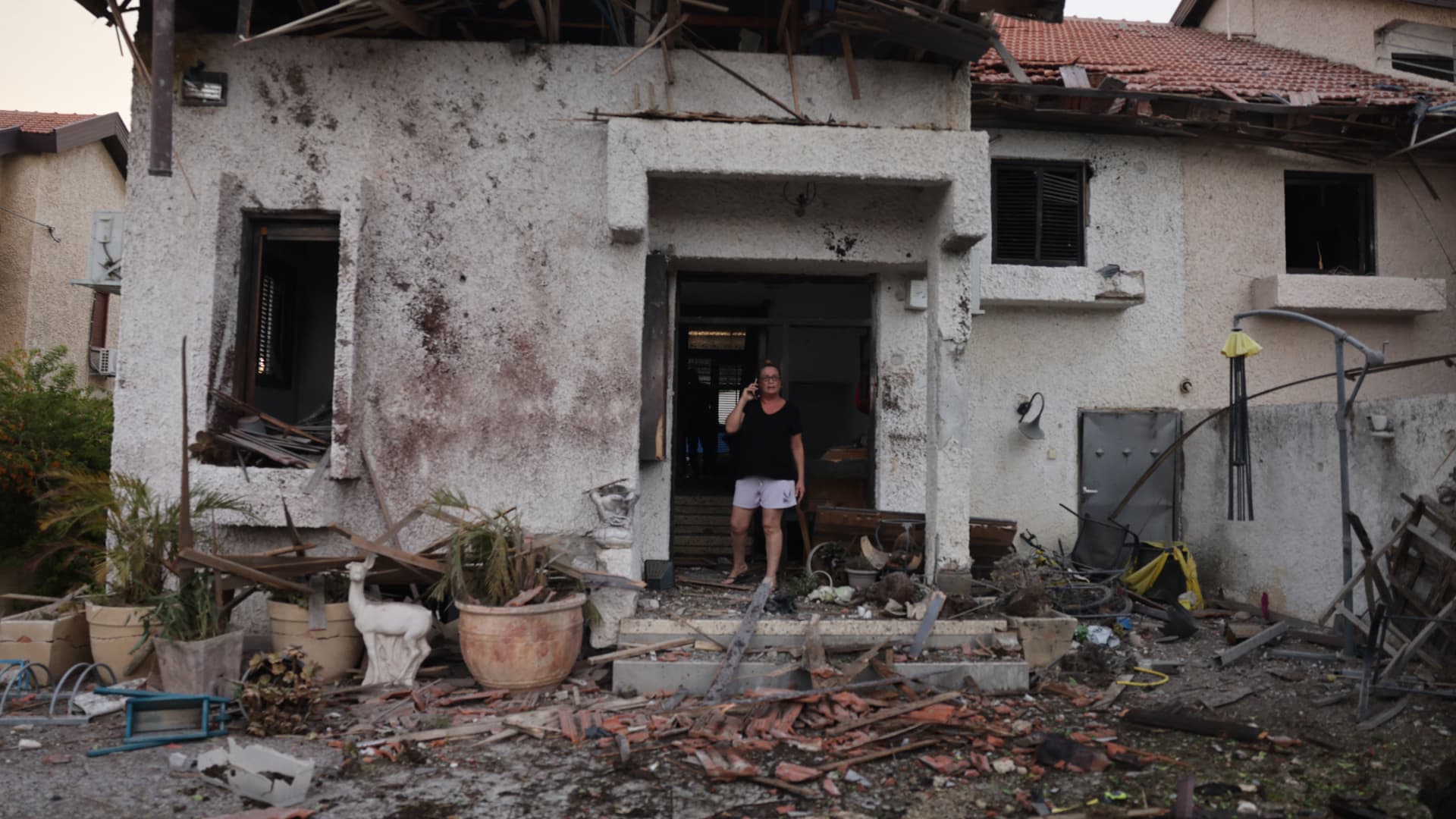 A woman stands at the entrance of a damaged house in the southern Israeli city of Ashkelon after a rocket attack from Gaza on October 9, 2023.