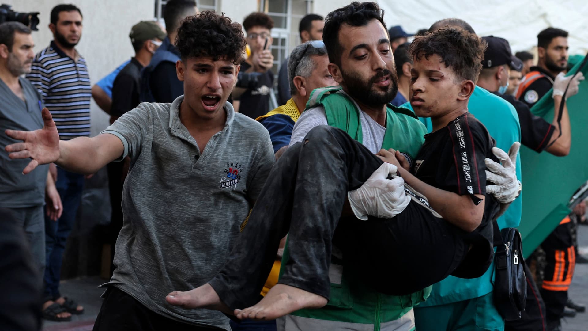 EDITORS NOTE: Graphic content / A man carries a wounded child into at al-Shifa hospital following Israeli strikes in Gaza City on October 10, 2023.