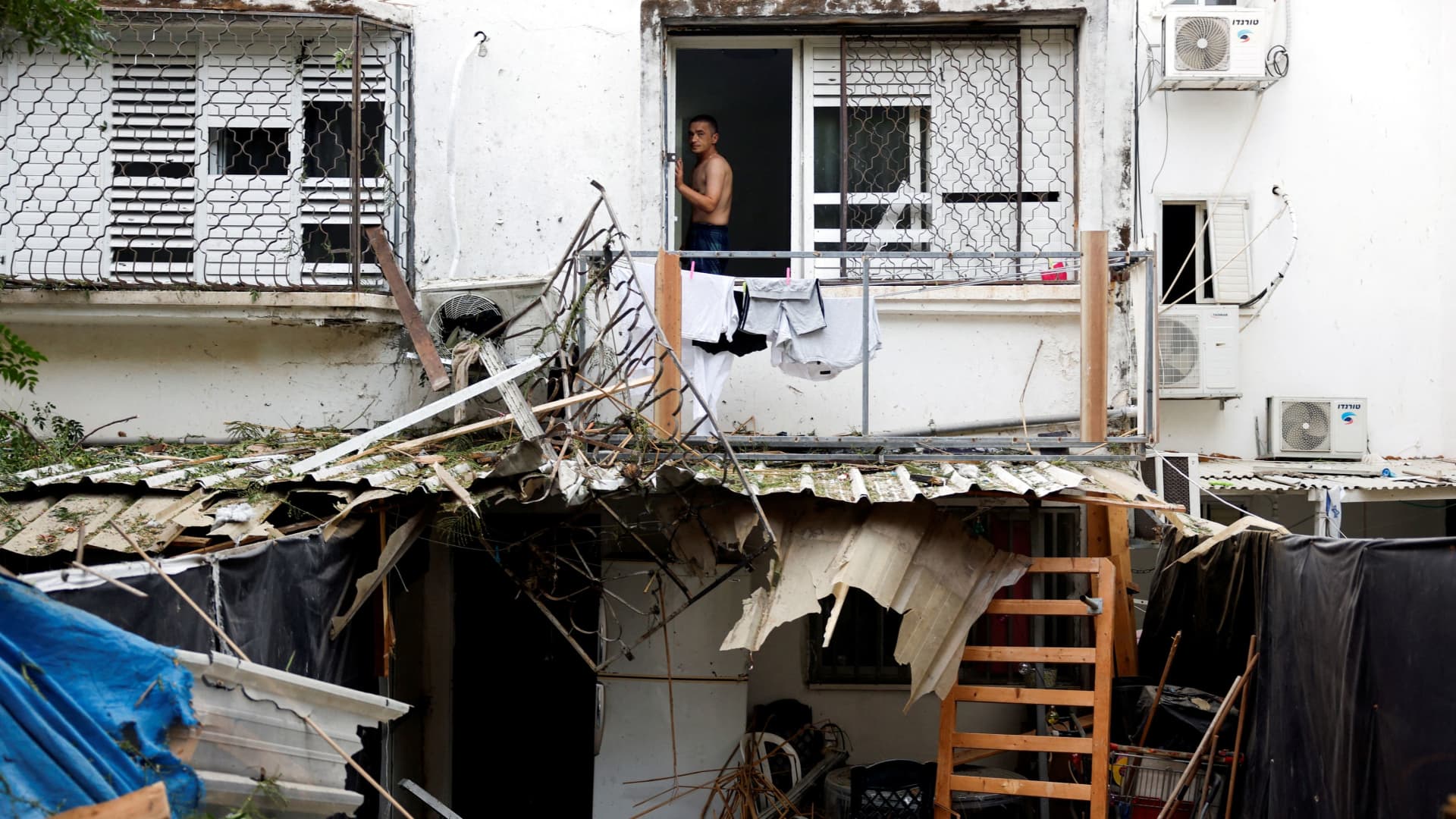An Israeli man looks out from a window of a building that was hit following rockets from Gaza that were launched towards Israel in Ashkelon, southern Israel October 9, 2023.