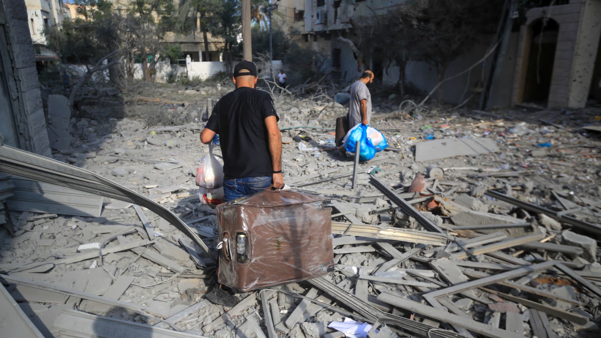 Palestinians walk amid the rubble of destroyed and damaged building in the heavily bombarded city center of Khan Yunis in the southern Gaza Strip following overnight Israeli shelling, on October 10, 2023. 