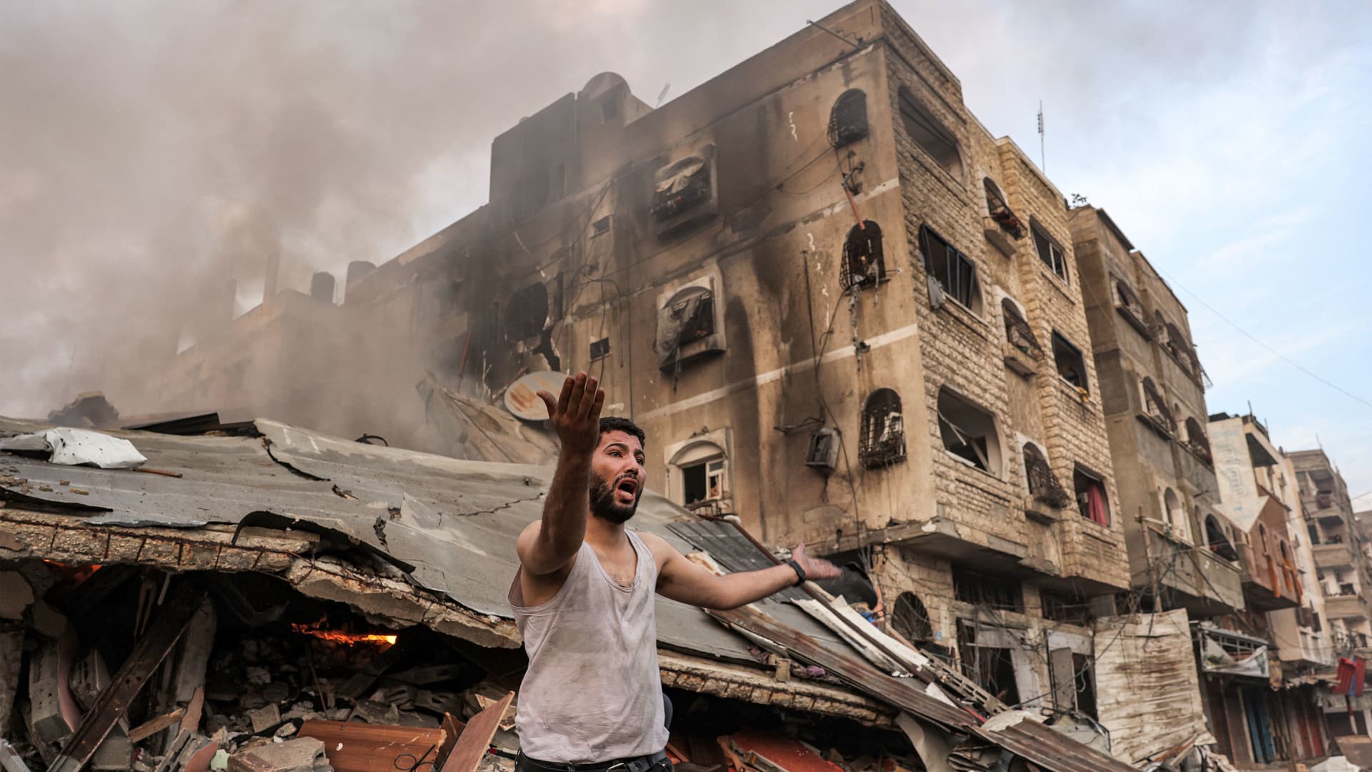 A man reacts outside a burning collapsed building following Israeli bombardment in Gaza City, on Oct.11, 2023.