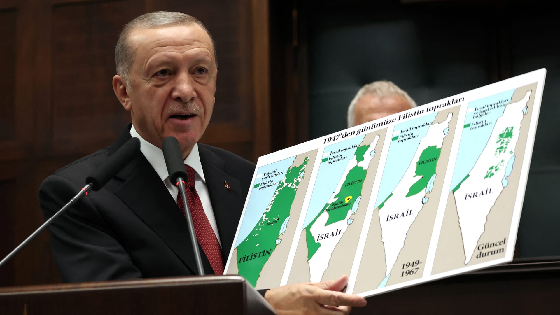 Turkish President Tayyip Erdogan holds a sign showing the evolution of lands of Israel and Palestine at his party's group meeting in the Turkish Grand National Assembly in Ankara, Turkey on Oct. 11, 2023.