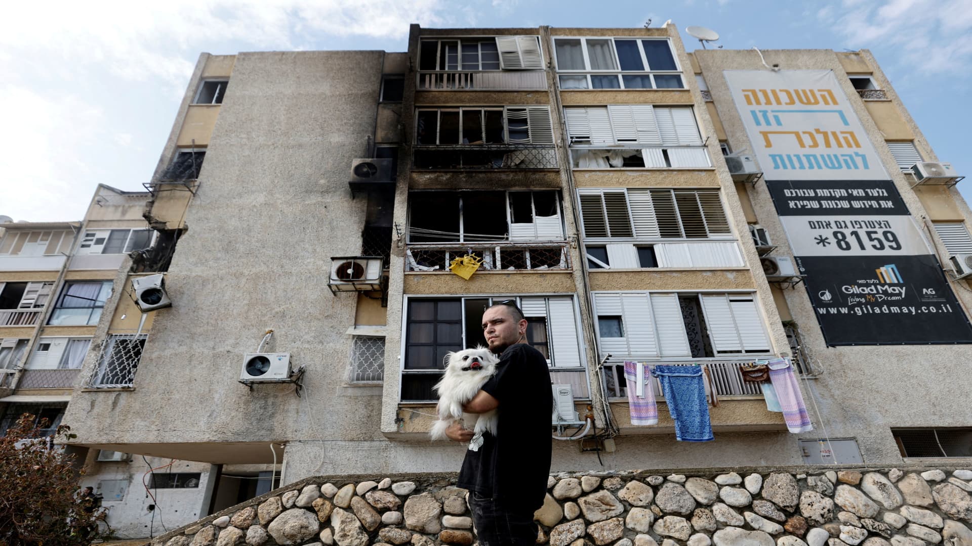 A man holds his dog after a rocket, launched from the Gaza Strip, landed in Ashkelon, southern Israel, October 11, 2023. 