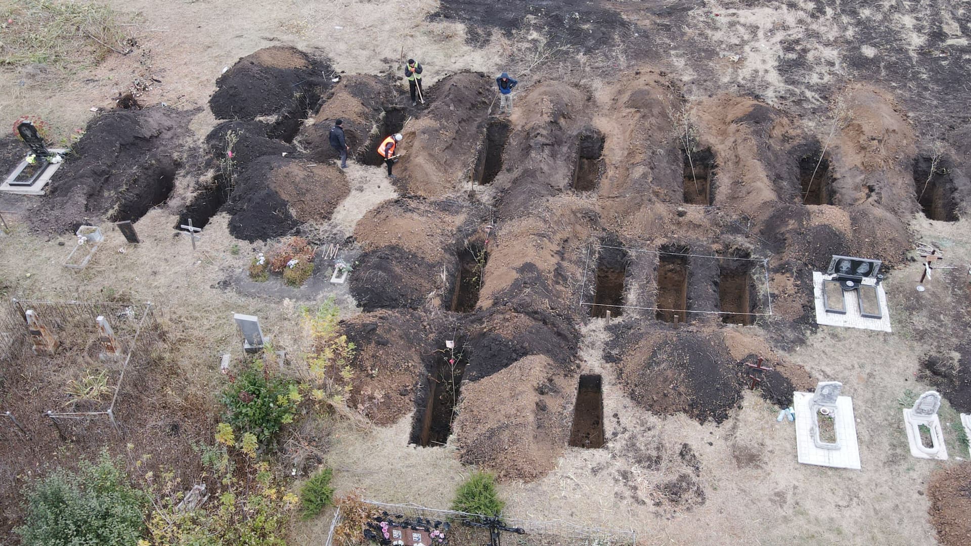 An aerial photograph taken with a drone shows workers digging graves for the victims of an airstrike earlier in the month, at the cemetery in the Groza village, Kharkiv region, on October 9, 2023, amid the Russian invasion of Ukraine.
