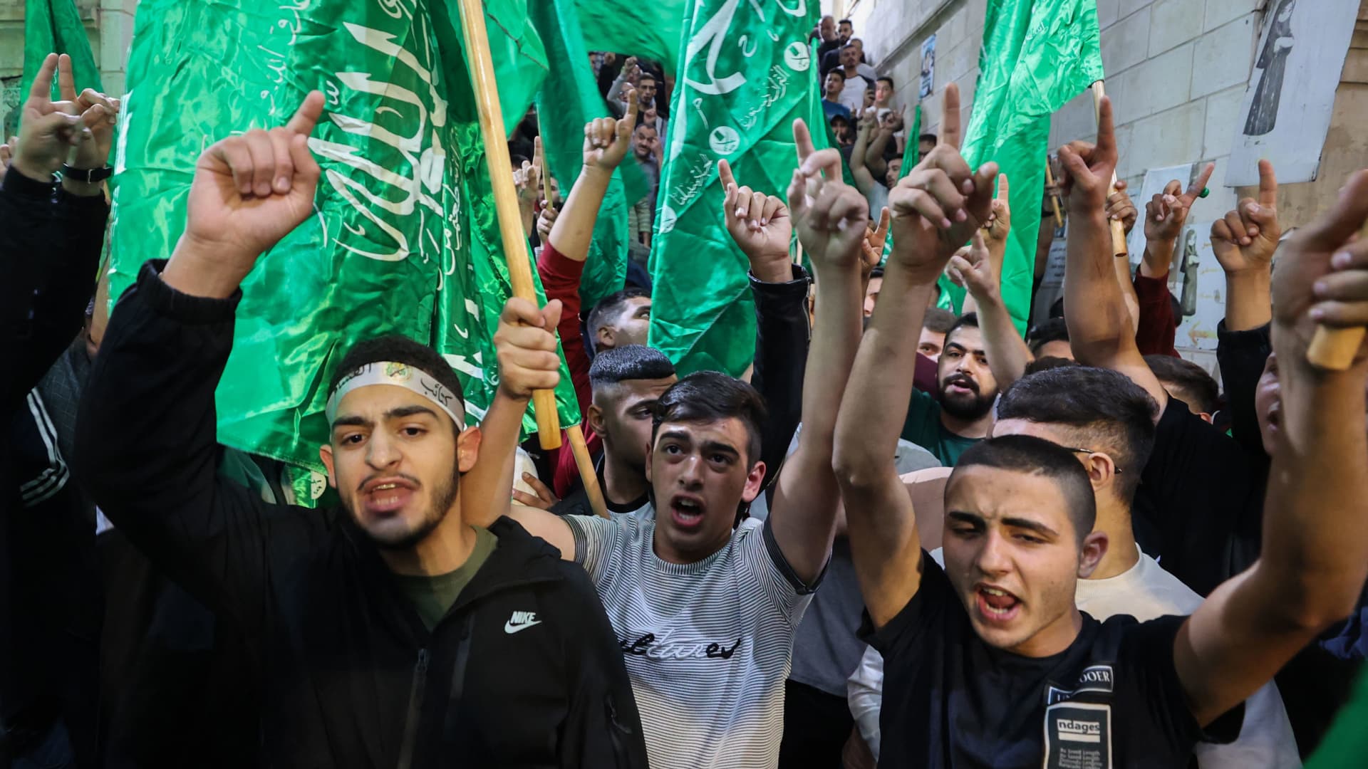 Palestinians lift Hamas movement flags as they protest in Nablus city in the occupied West Bank following an airstrike on a Gaza hospital compound killing hundreds on October 17, 2023.