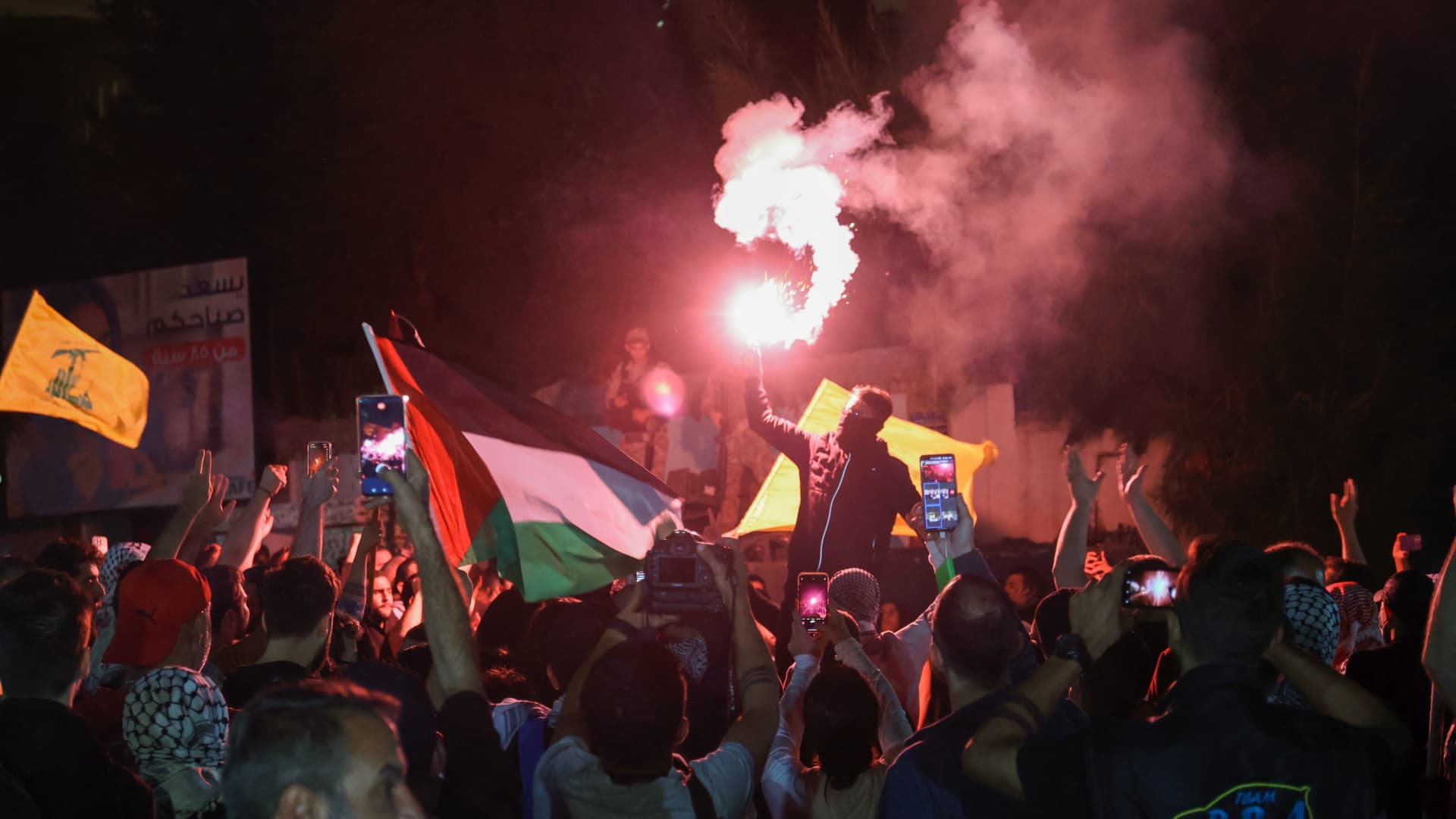 Protesters light a flare during a rally in front of the French embassy complex in Beirut early on October 18, 2023, in support of Palestinians after a strike on the Ahli Arab hospital in central Gaza that killed hundreds. 