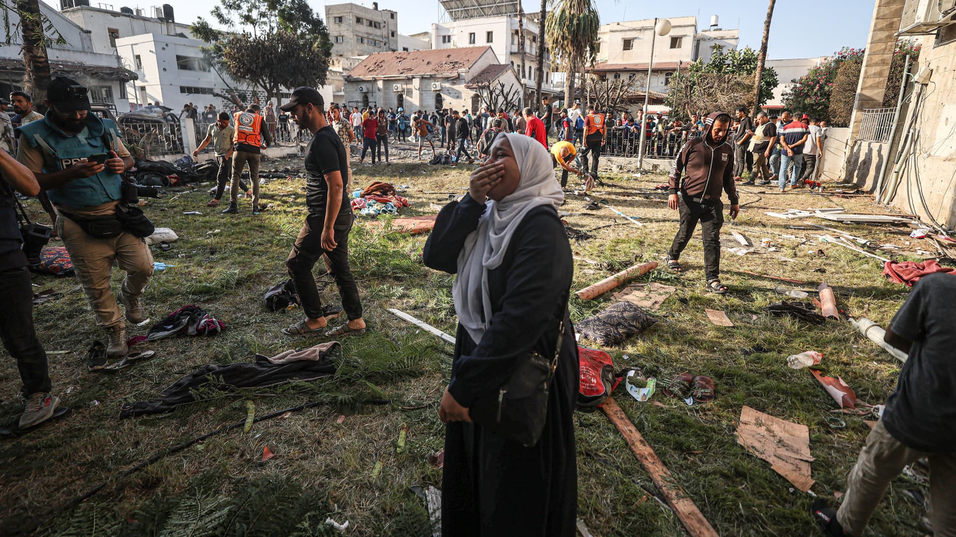 A Palestinian woman cries amid debris and the belongings of Palestinians in the garden of al-Ahli Arabi Baptist Hospital in Gaza City, Gaza, after hundreds of people were killed when the hospital was hit, Oct. 18, 2023.