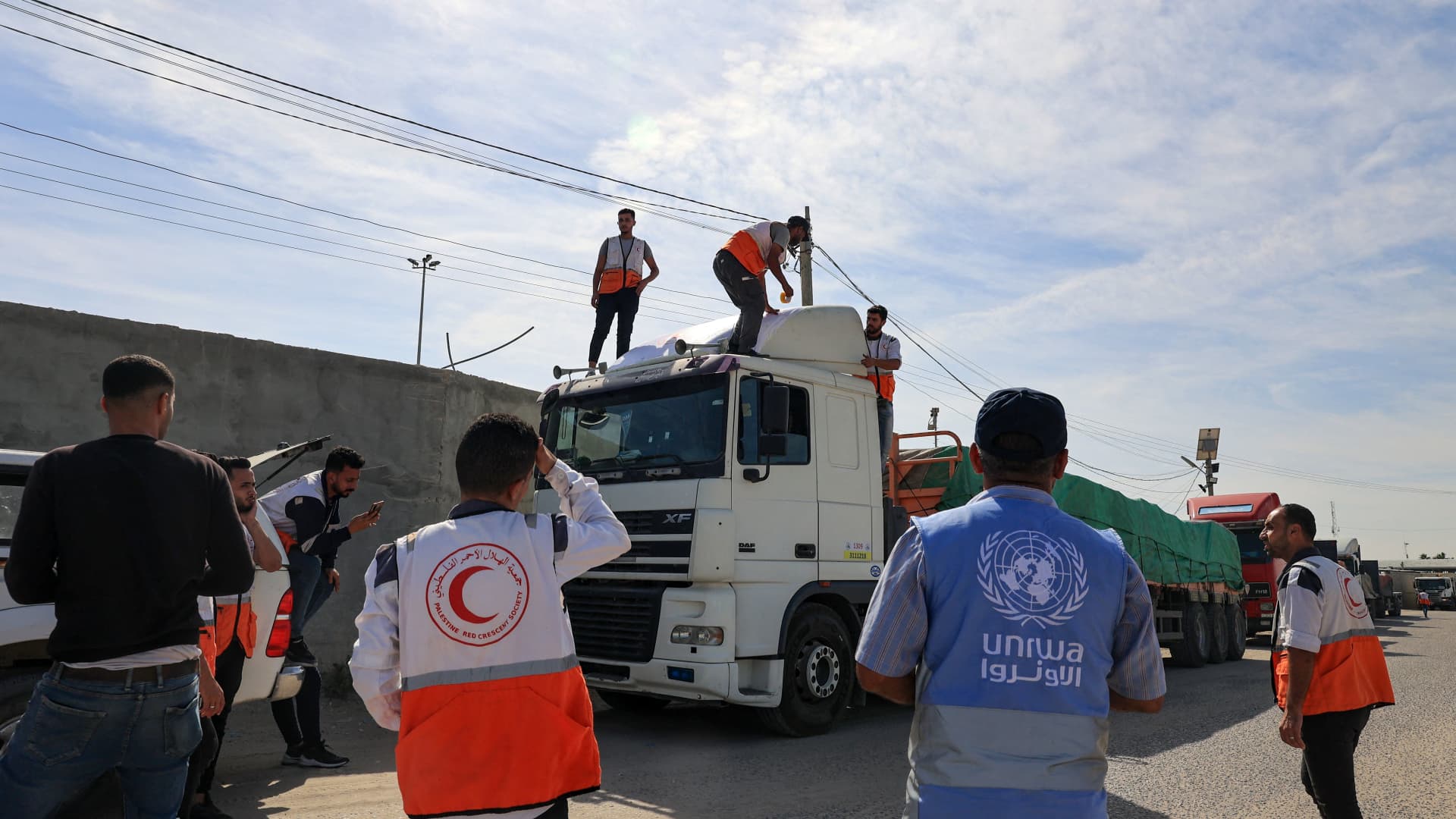 Aid workers gather around trucks carrying humanitarian aid that entered the Gaza Strip from Egypt via the Rafah border crossing on October 21, 2023. 